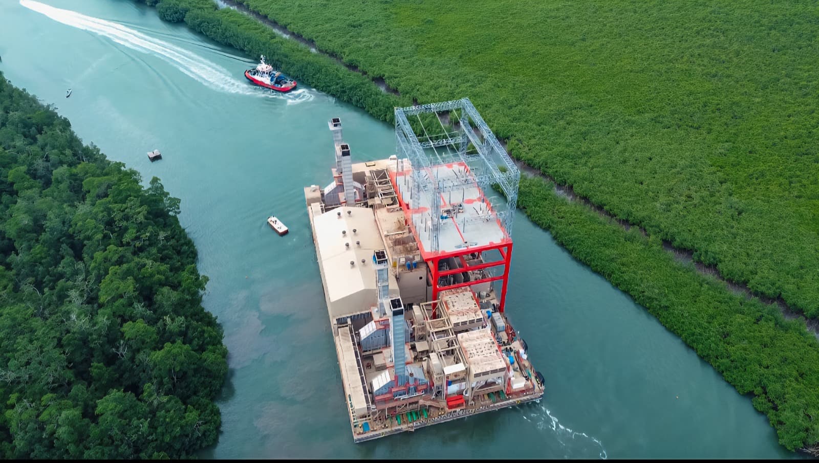 La barge electrique de Karpowership remorquee sur un chenal borde de mangroves, a son arrivee au Gabon