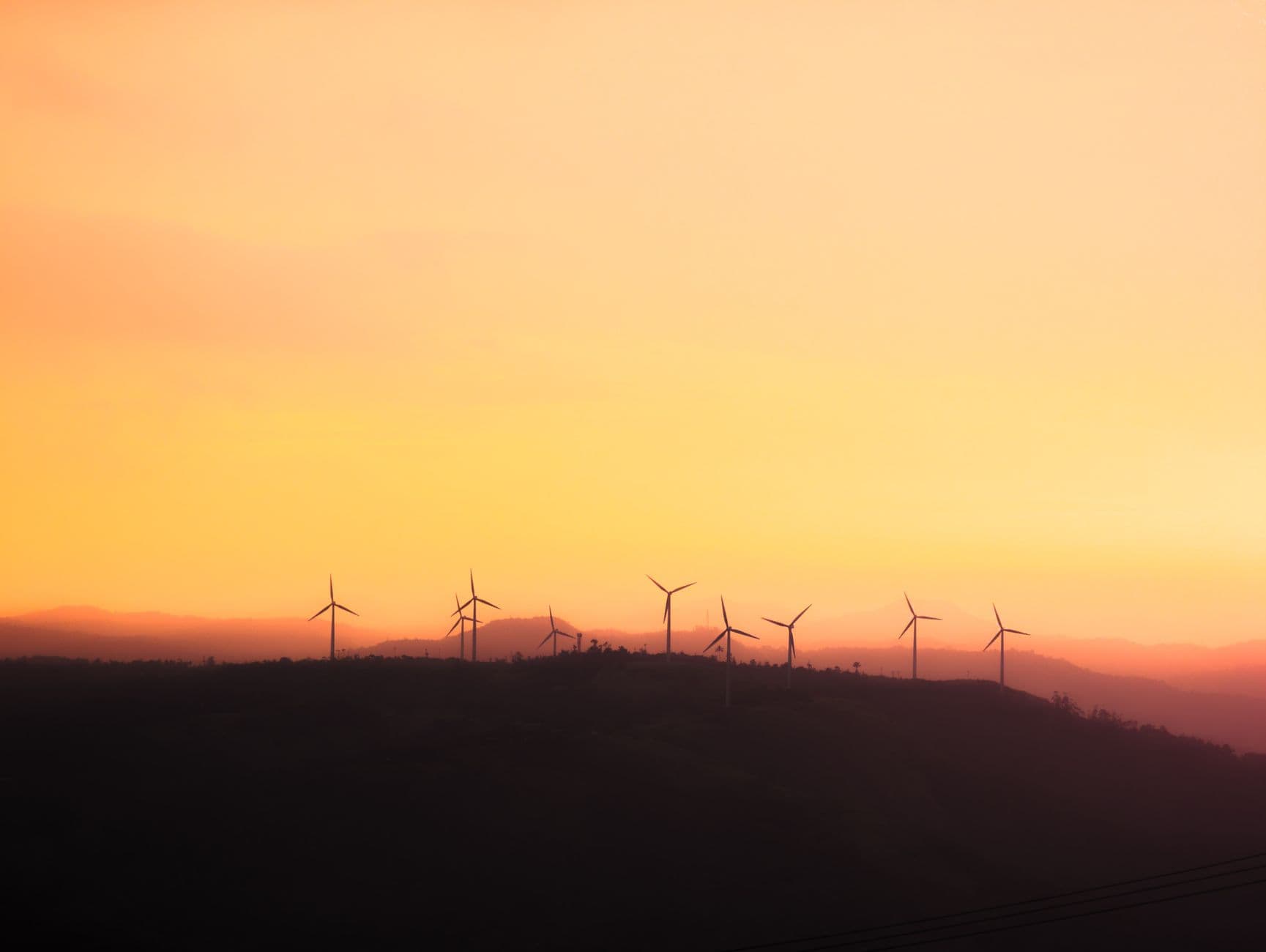 Nacelles d'éoliennes en usine près d'une tablette affichant une courbe verte en hausse.