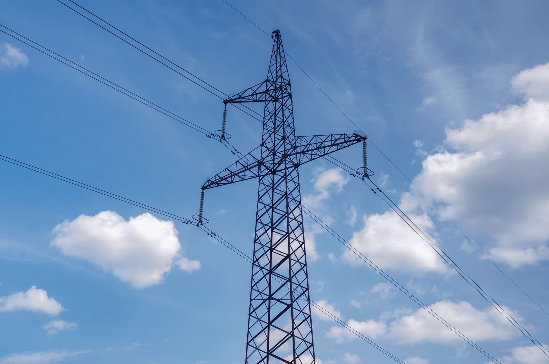 Des groupes diesel devant une ligne à haute tension et une grande centrale électrique au loin.